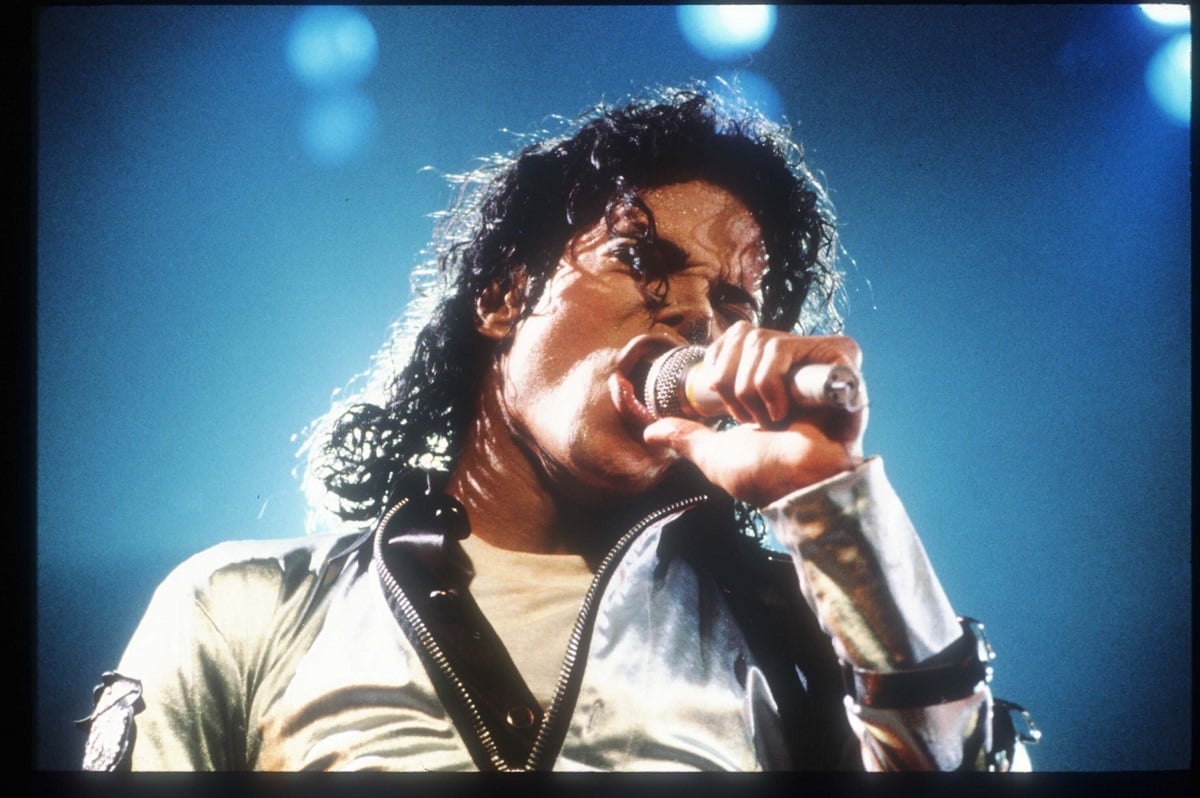 Michael Jackson wearing a gold jacket while singing at a concert.