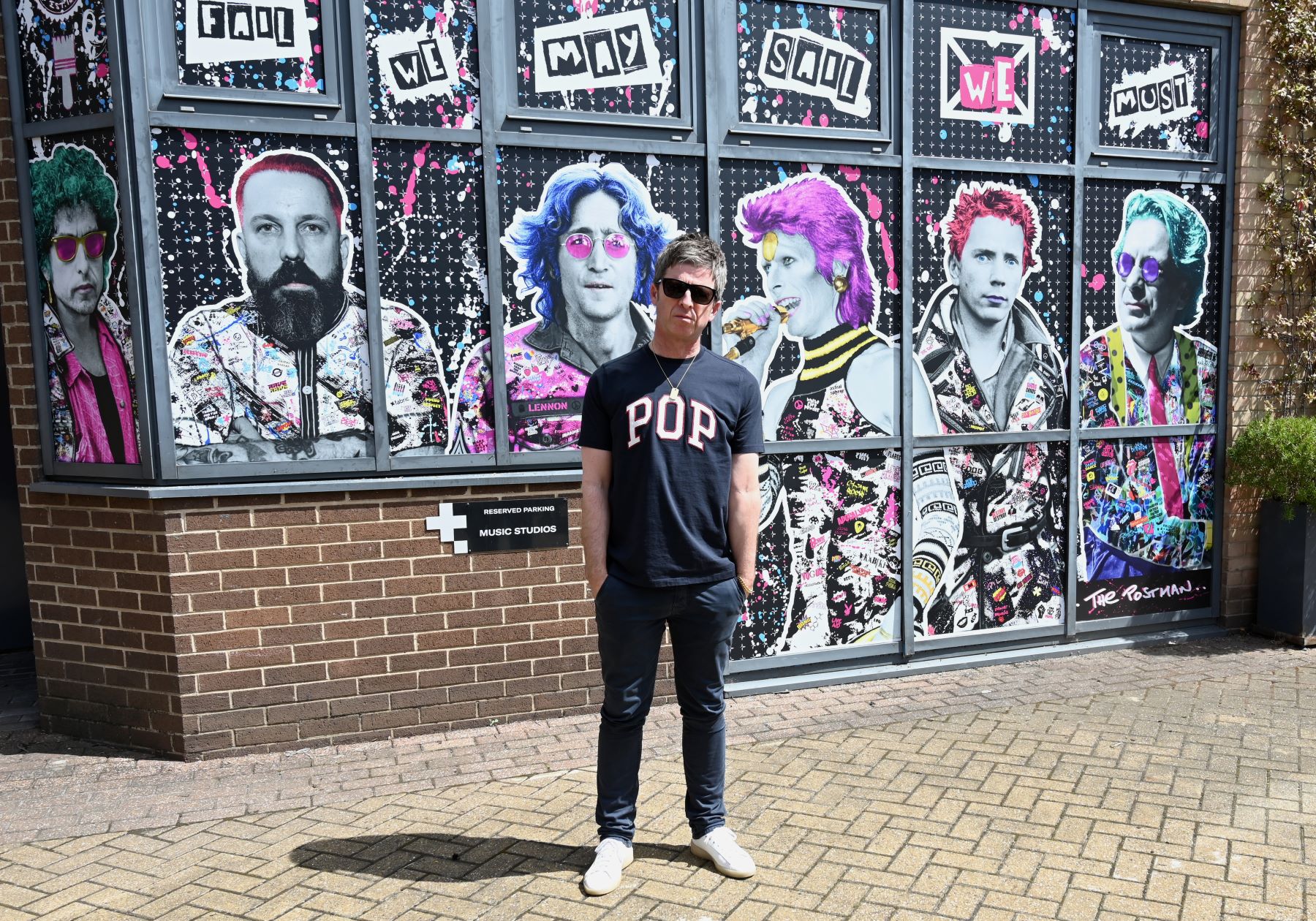 Noel Gallagher posing at completed The Postman art mural in London, England