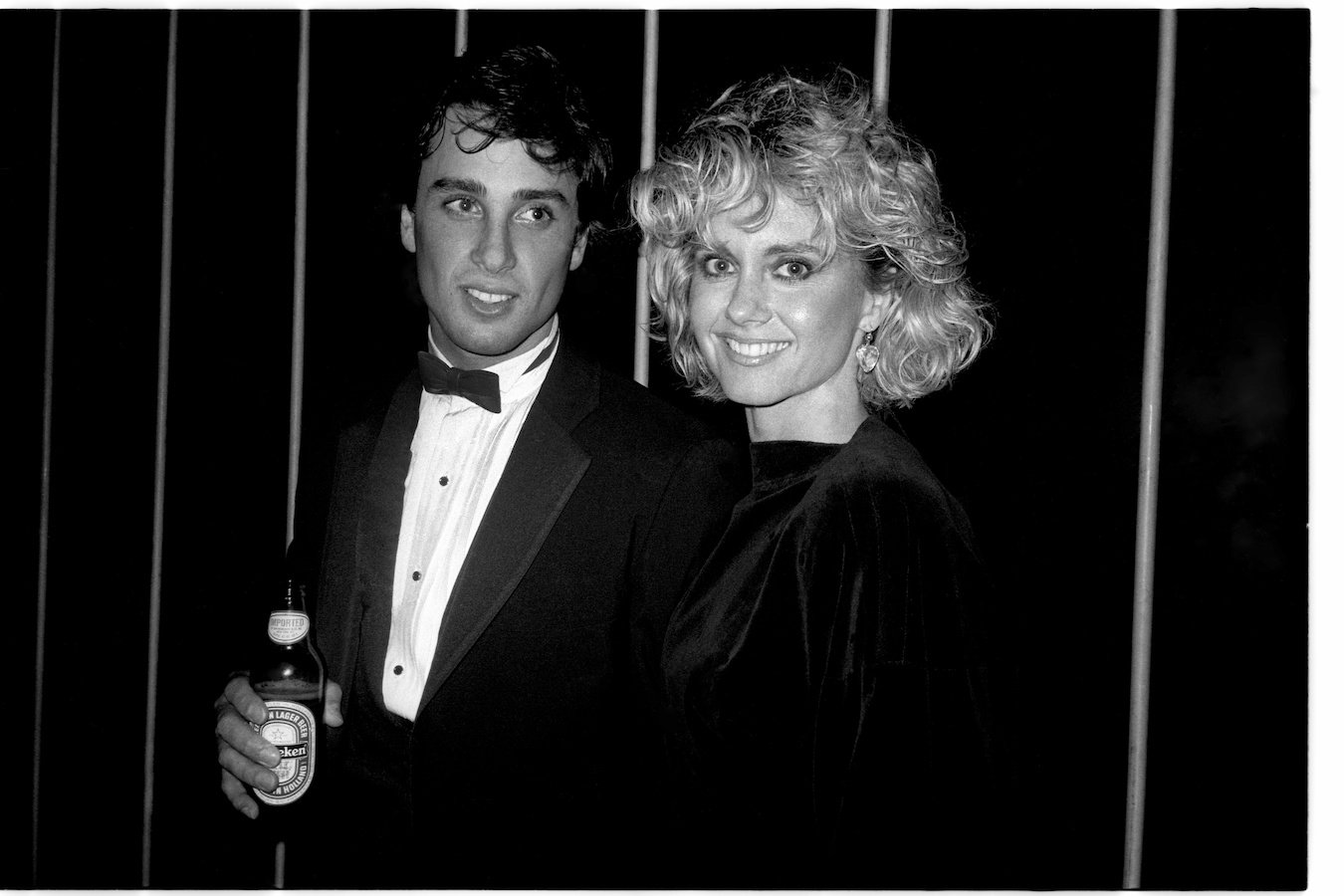 A black and white photo of Olivia Newton-John smiling with her husband Matt Lattanzi