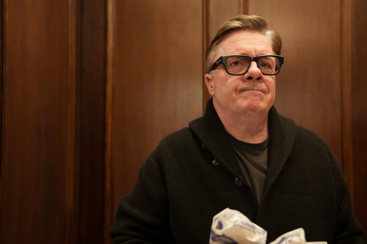 Nathan Lane as Teddy in Only Murders in the Building. Teddy wears a brown sweater and glasses. 