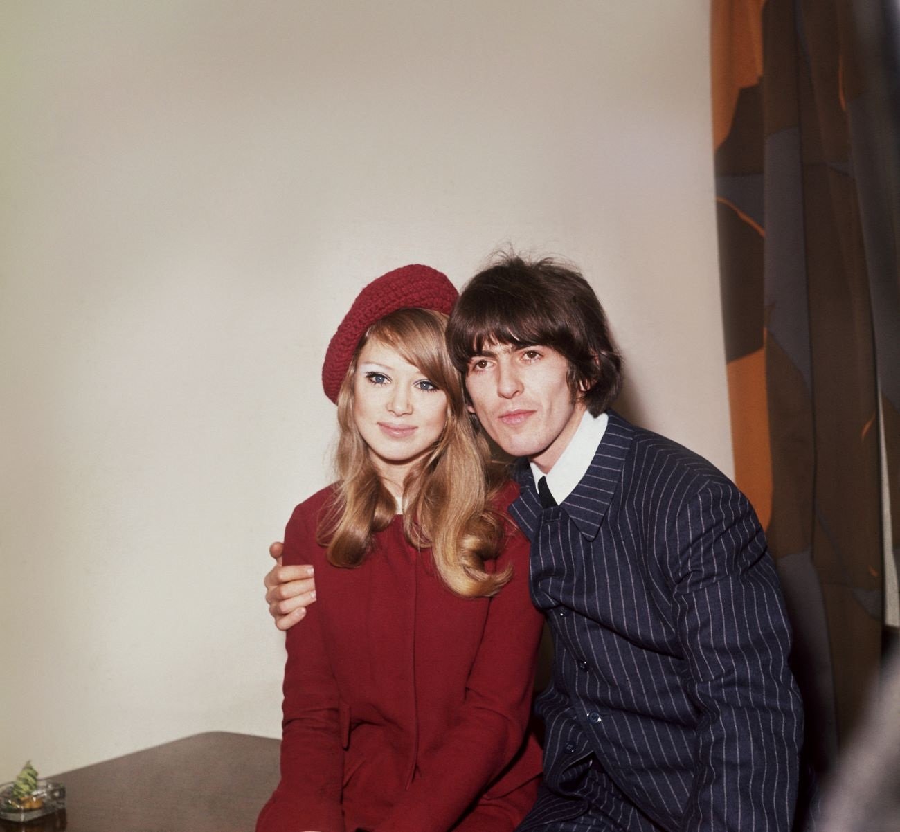George Harrison sits with his arm around Pattie Boyd's shoulders.