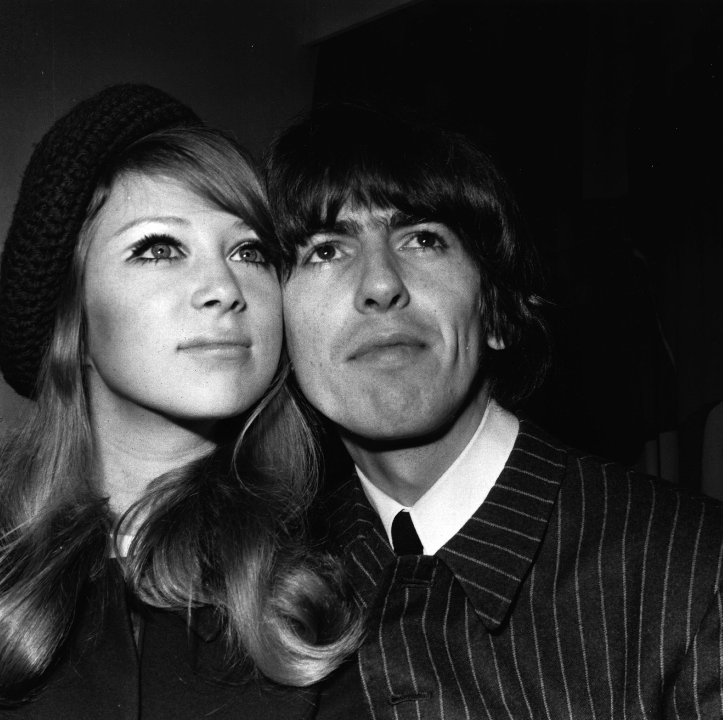 A black and white picture of Pattie Boyd and George Harrison posing cheek to cheek.