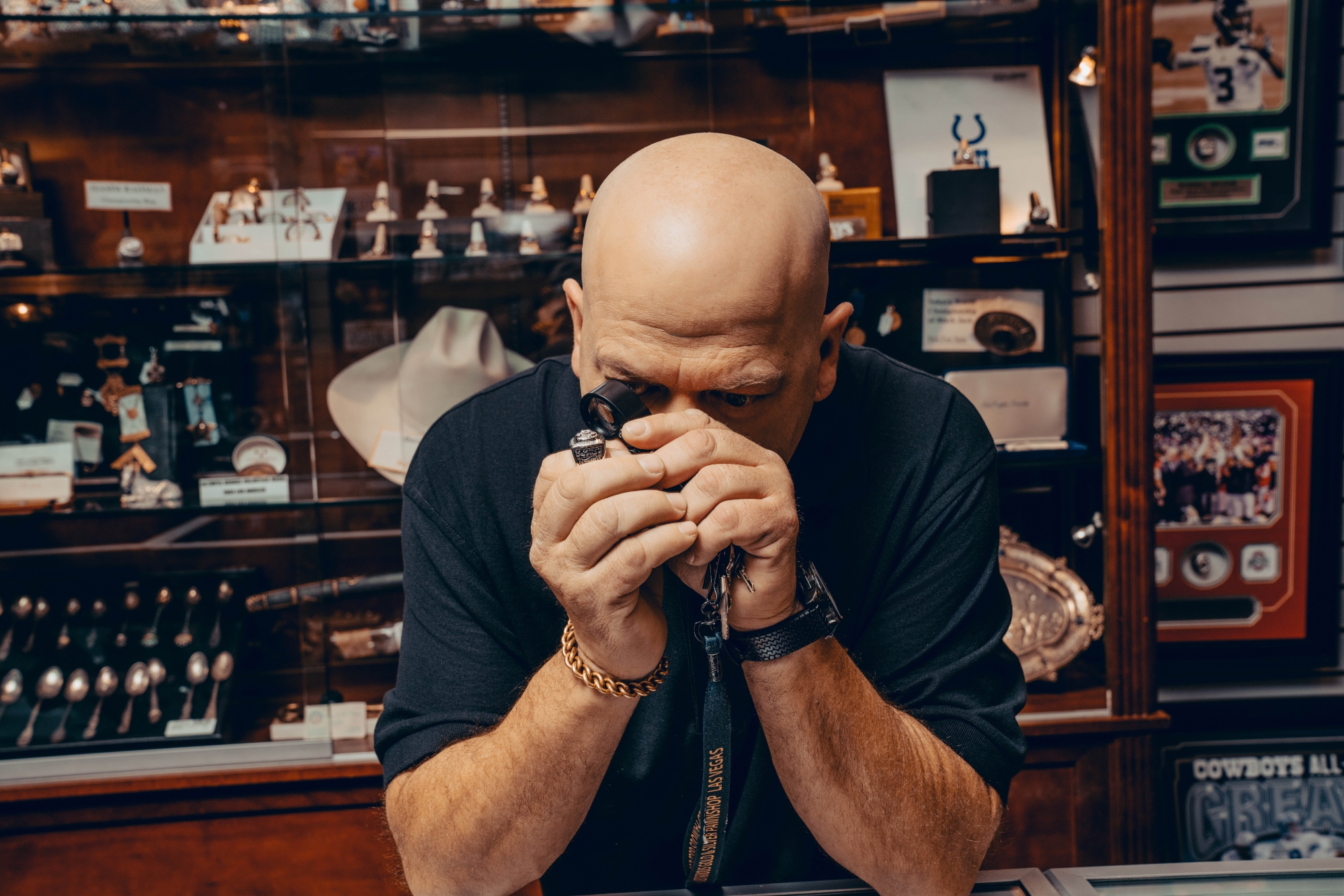 'Pawn Stars' Rick Harrison with his elbows resting on a table looking at an item with an eyeglass