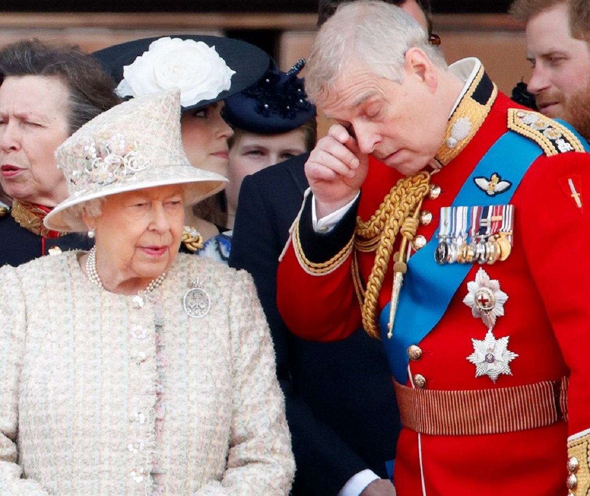 Prince Andrew, who is reportedly seeking Queen Elizabeth II's help about his future, rubbing his eye as he stands next to her on the Buckingham Palace balcony