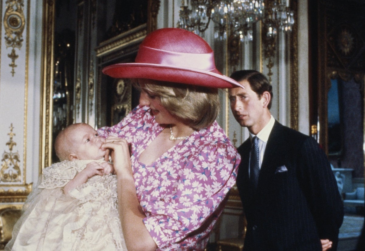 Princess Diana holding Prince William on the day of his christening with Prince Charles in the background