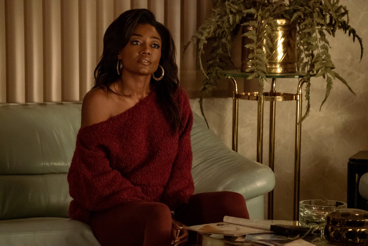 Patina Miller as Raq Thomas wearing a red sweater set and sitting on her couch in 'Power Book III: Raising Kanan'
