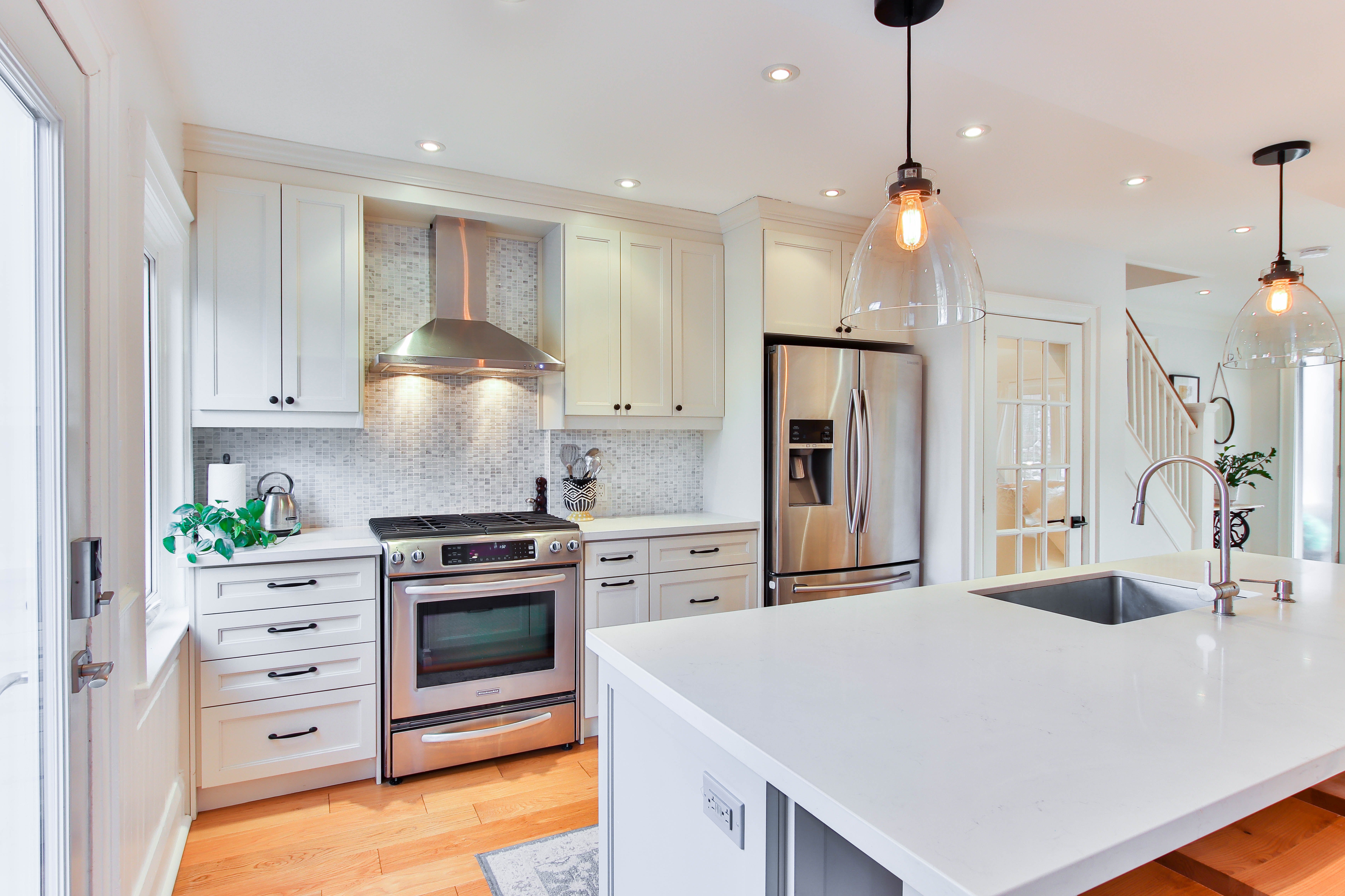 A renovated kitchen with new appliances, white countertops, and overhead lighting.