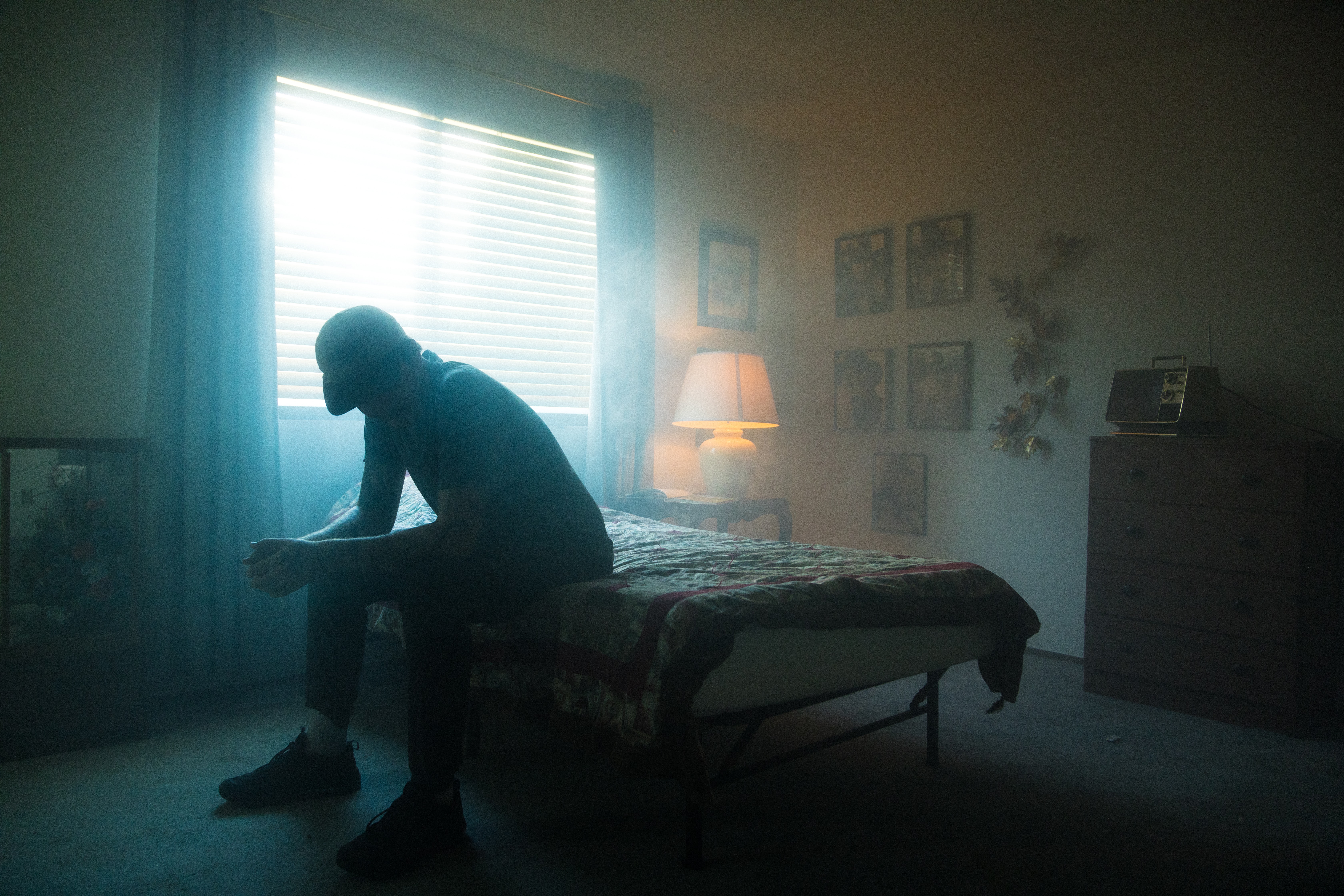 A man sits alone on his bed.