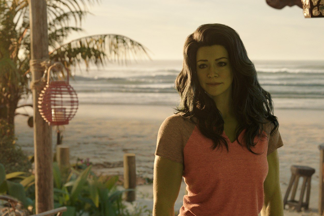 Tatiana Maslany, in character as Jennifer Walters/She-Hulk in 'She-Hulk: Attorney at Law,' wears a pink shirt on a beach.
