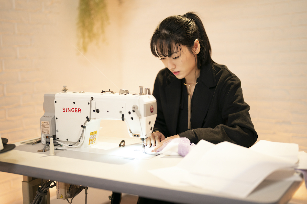 Sienna Li working on her sewing machine in Season 3 of 