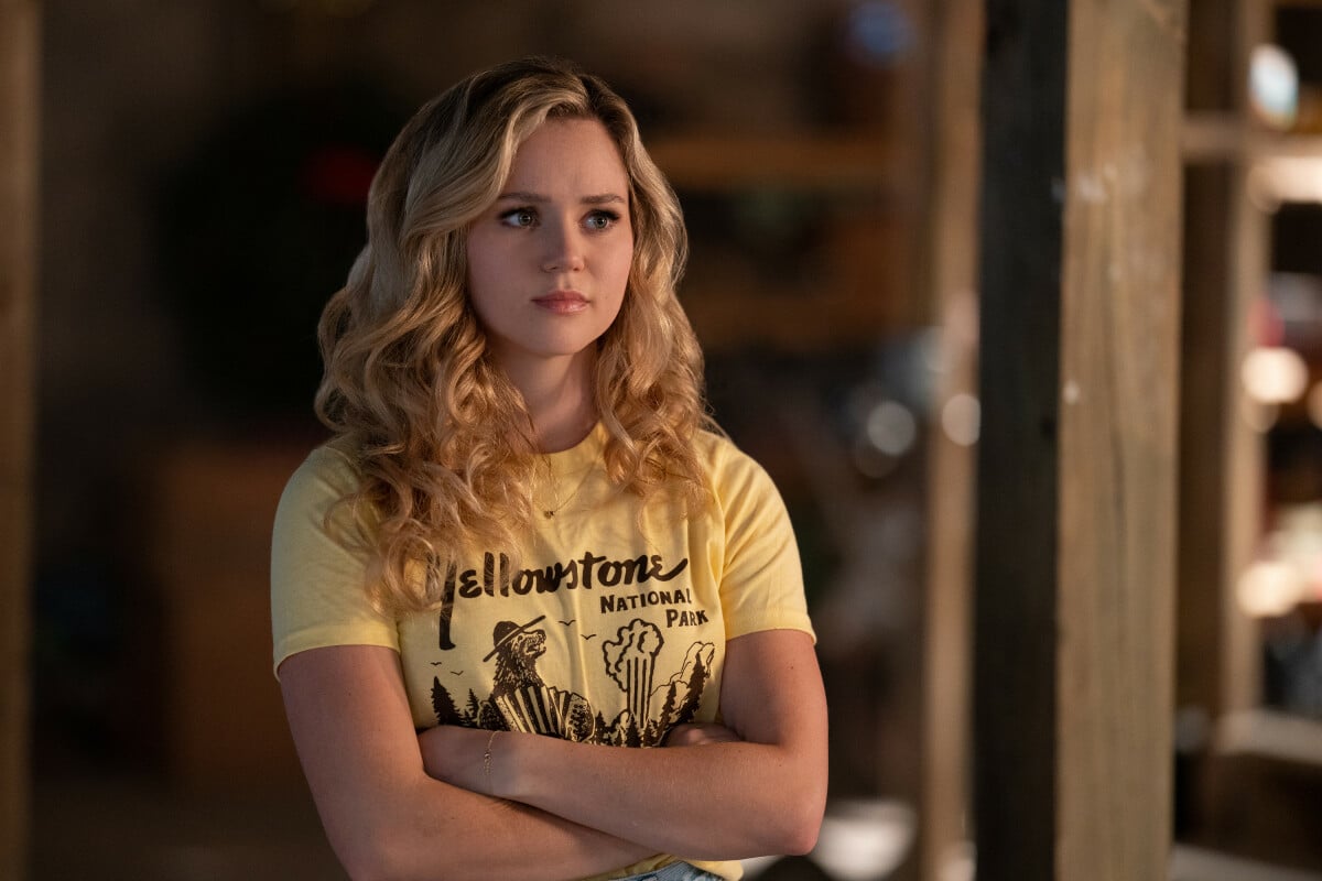 Brec Bassinger, in character as Courtney Whitmore in 'Stargirl' Season 3 on The CW, wears a yellow shirt that reads, 'Yellowstone National Park.'