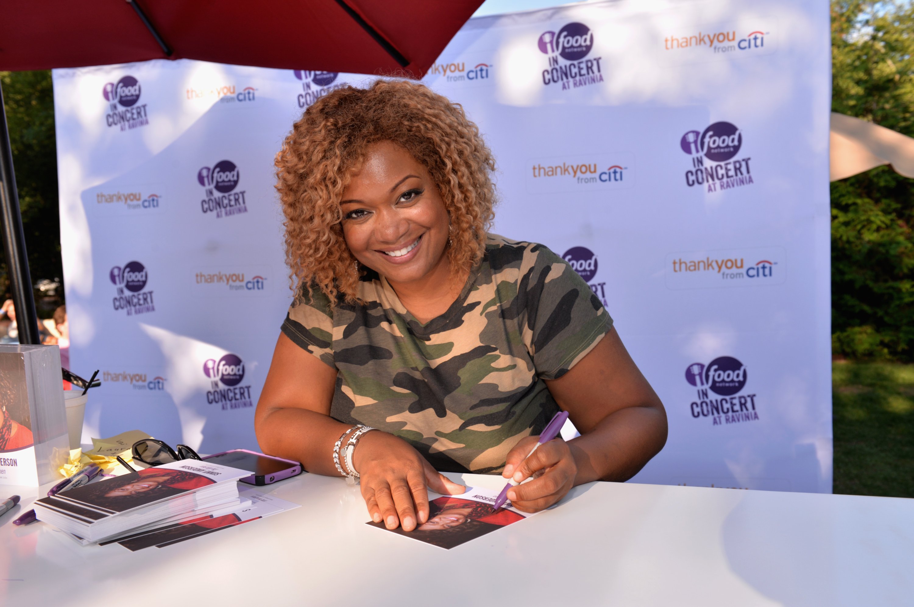 Food Network star Sunny Anderson smiles as she signs autographs at a Food Network event.