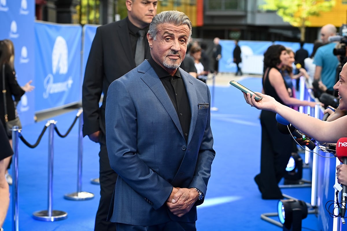 Sylvester Stallone posing while wearing a blue suit.