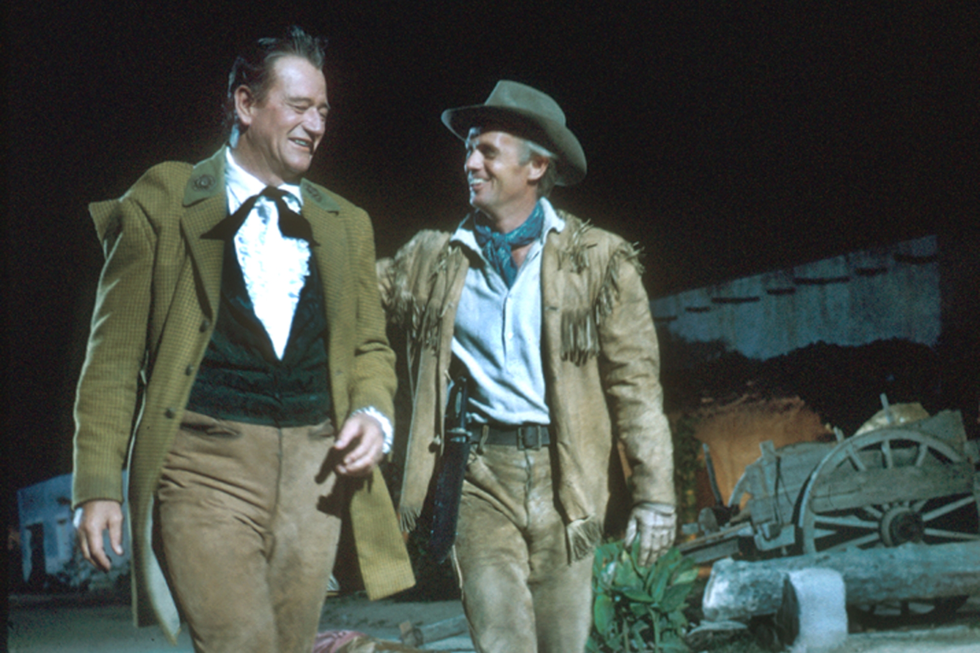 'The Alamo' John Wayne as Col. Davy Crockett and Richard Widmark as Col. Jim Bowie smiling as they walk alongside one another wearing Western clothes