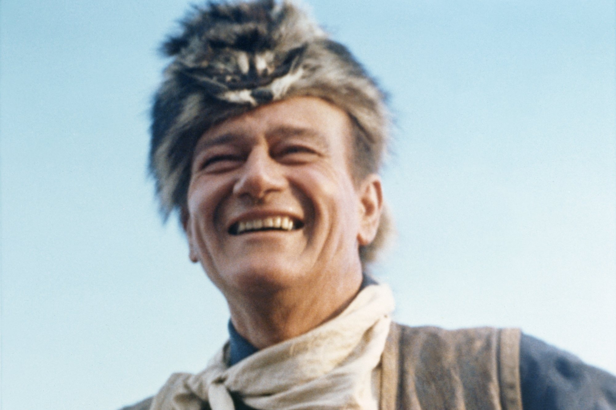 'The Alamo' film John Wayne smiling wearing a fur cap and a white scarf