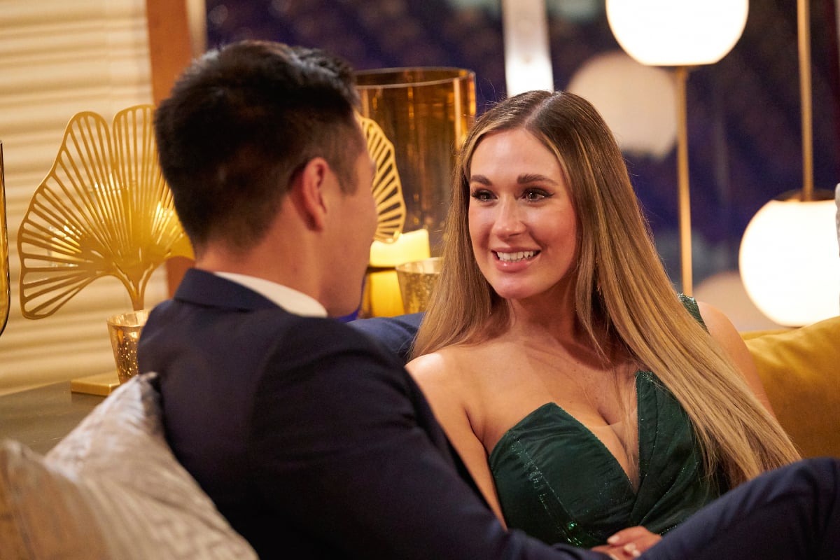 The Bachelorette 2022 lead Rachel Recchia recently explained why Fantasy Suites are so important. Rachel sits on the couch and talks with one of her contestants. She is wearing a green, strapless dress.