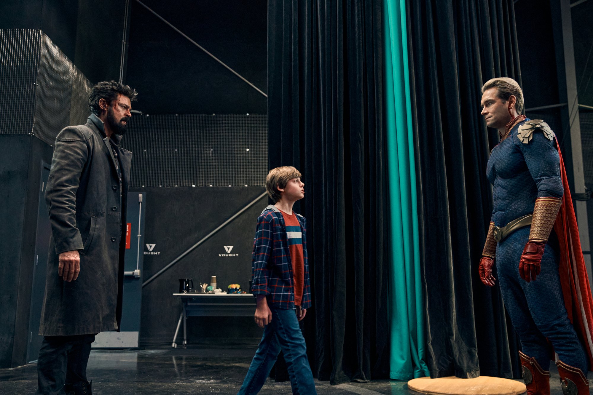 'The Boys' cast members Karl Urban, Cameron Crovetti, and Antony Starr as Billy Butcher, Ryan, and Homelander, all whom will appear in season 4. Butcher and Homelander are staring at each other, and Ryan is walking toward Homelander.