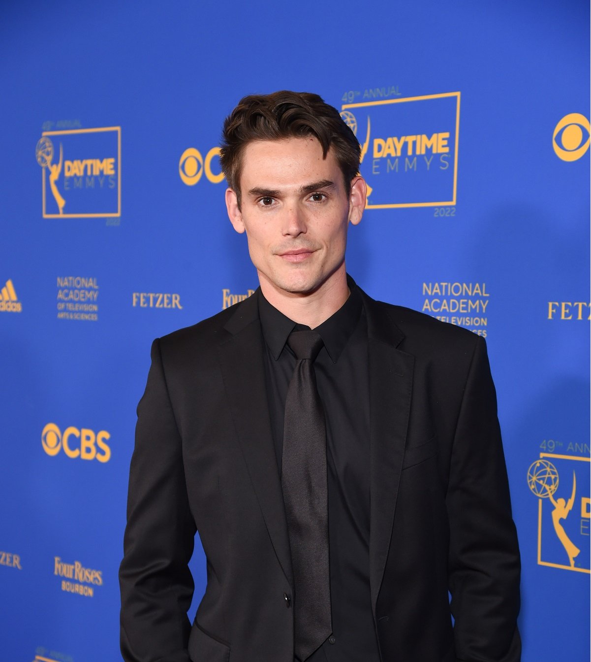 'The Young and the Restless' star Mark Grossman wearing a black suit while posing for a photo on the red carpet.