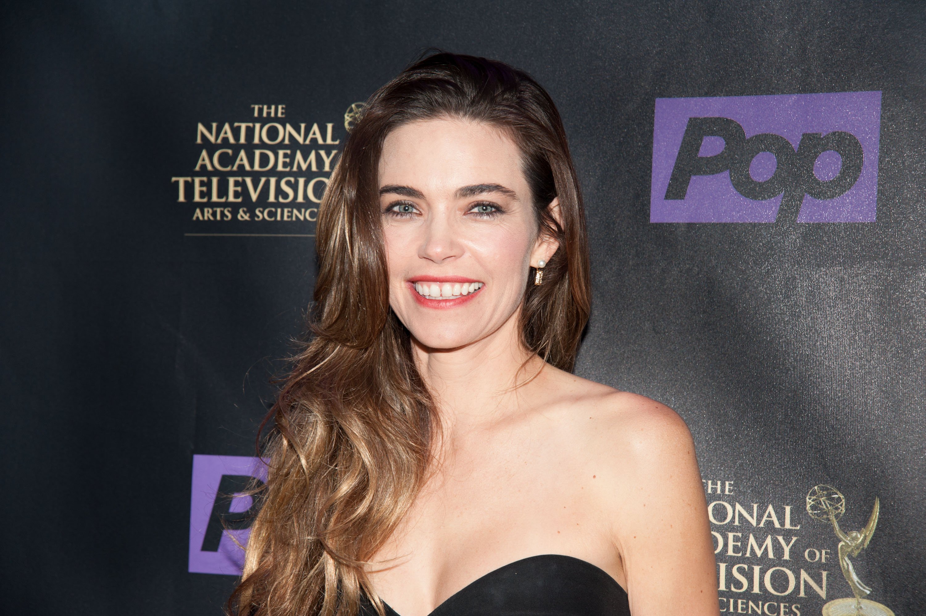 'The Young and the Restless' star Amelia Heinle wearing a black strapless dress and posing for photographers.