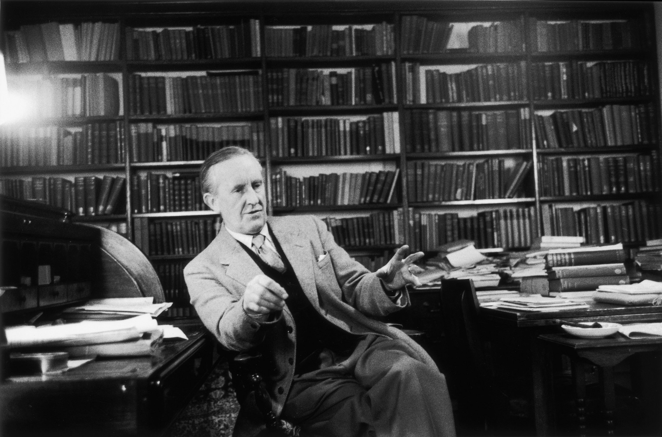 J.R.R. Tolkien, the author of 'The Hobbit' and 'The Lord Of The Rings sits for a photo in front of a stack of books