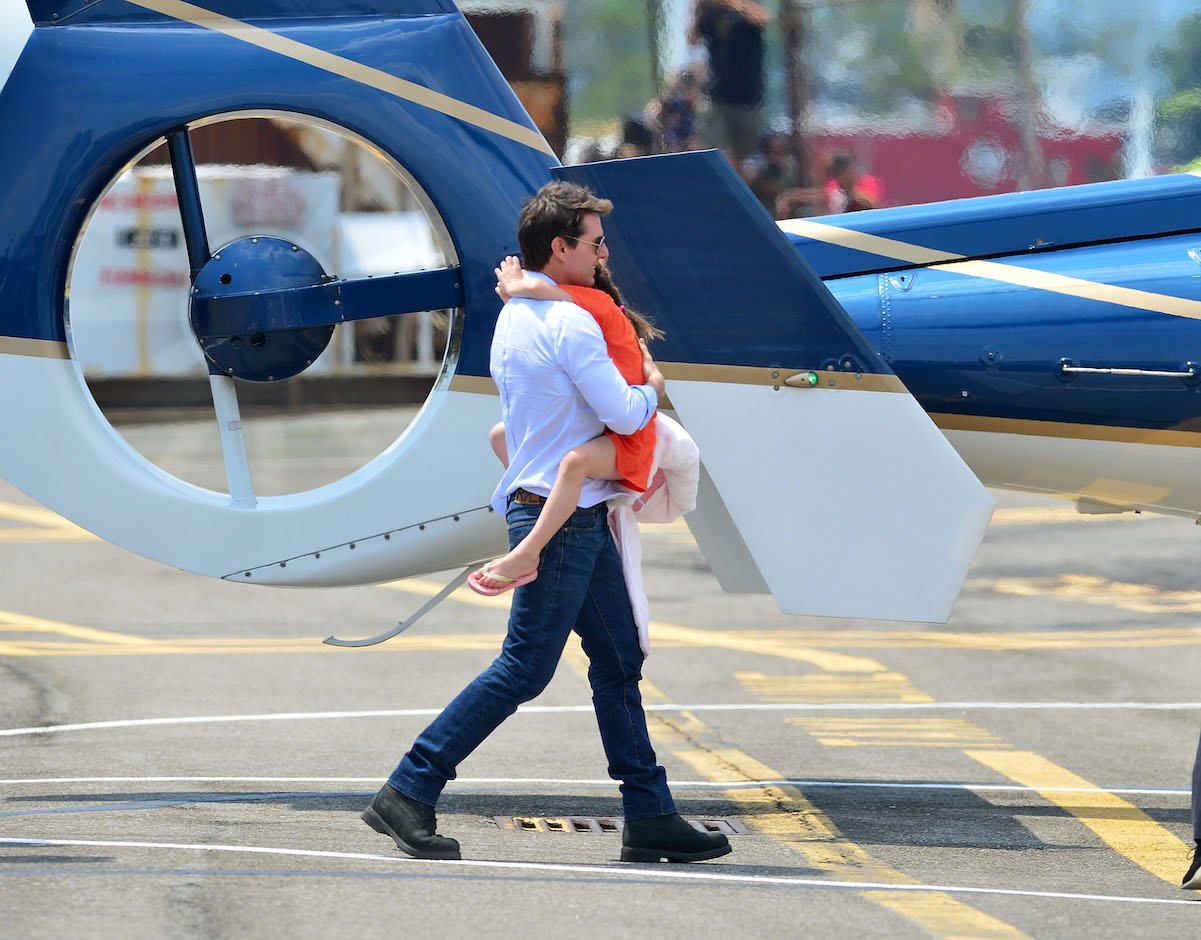 Tom Cruise, who has a net worth of $600 million, is seen walking while carrying Suri Cruise near a helicopter in 2012