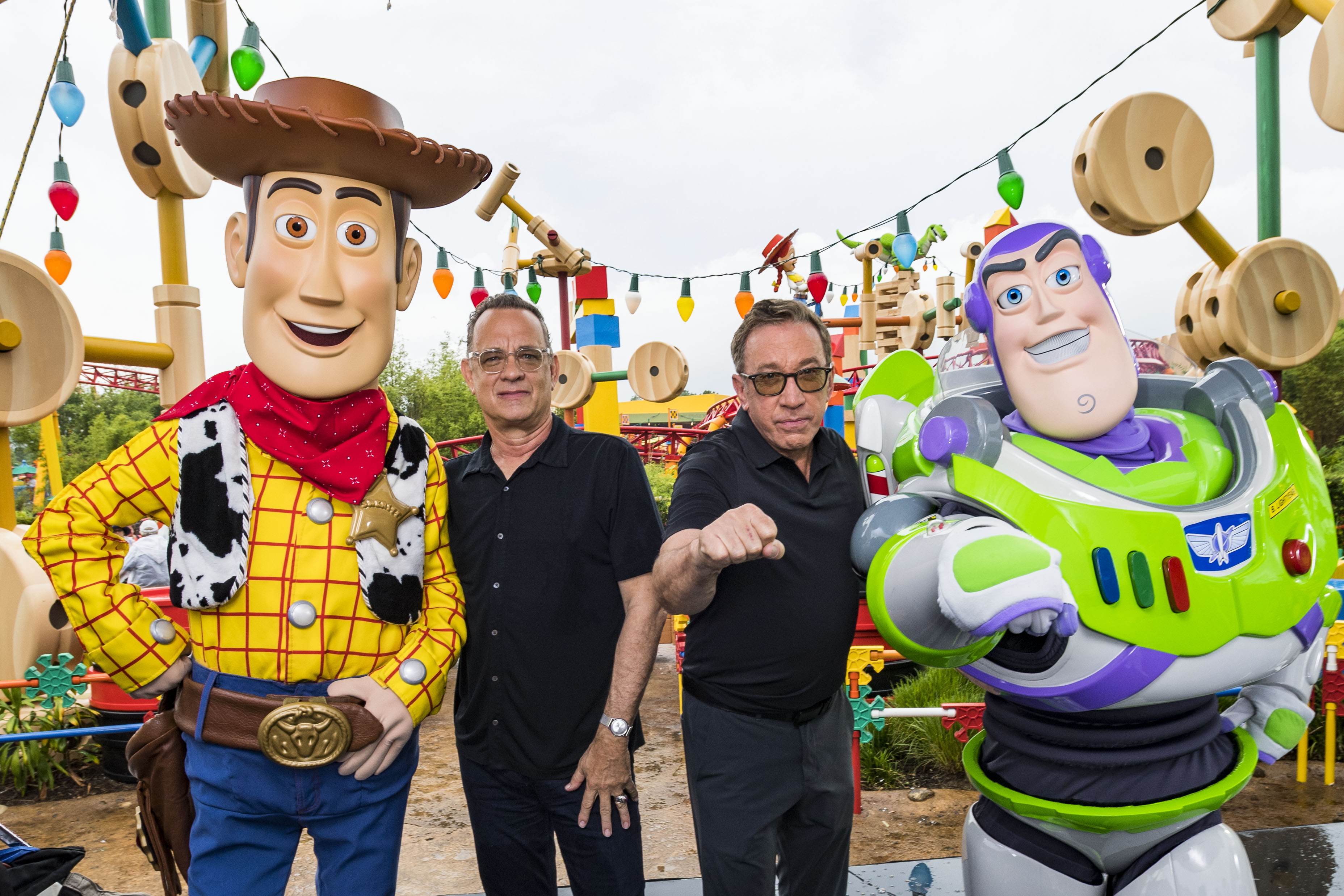 Tom Hanks and Tim Allen pose with Woody and Buzz Lightyear at Toy Story Land in Disney's Hollywood Studios in Florida