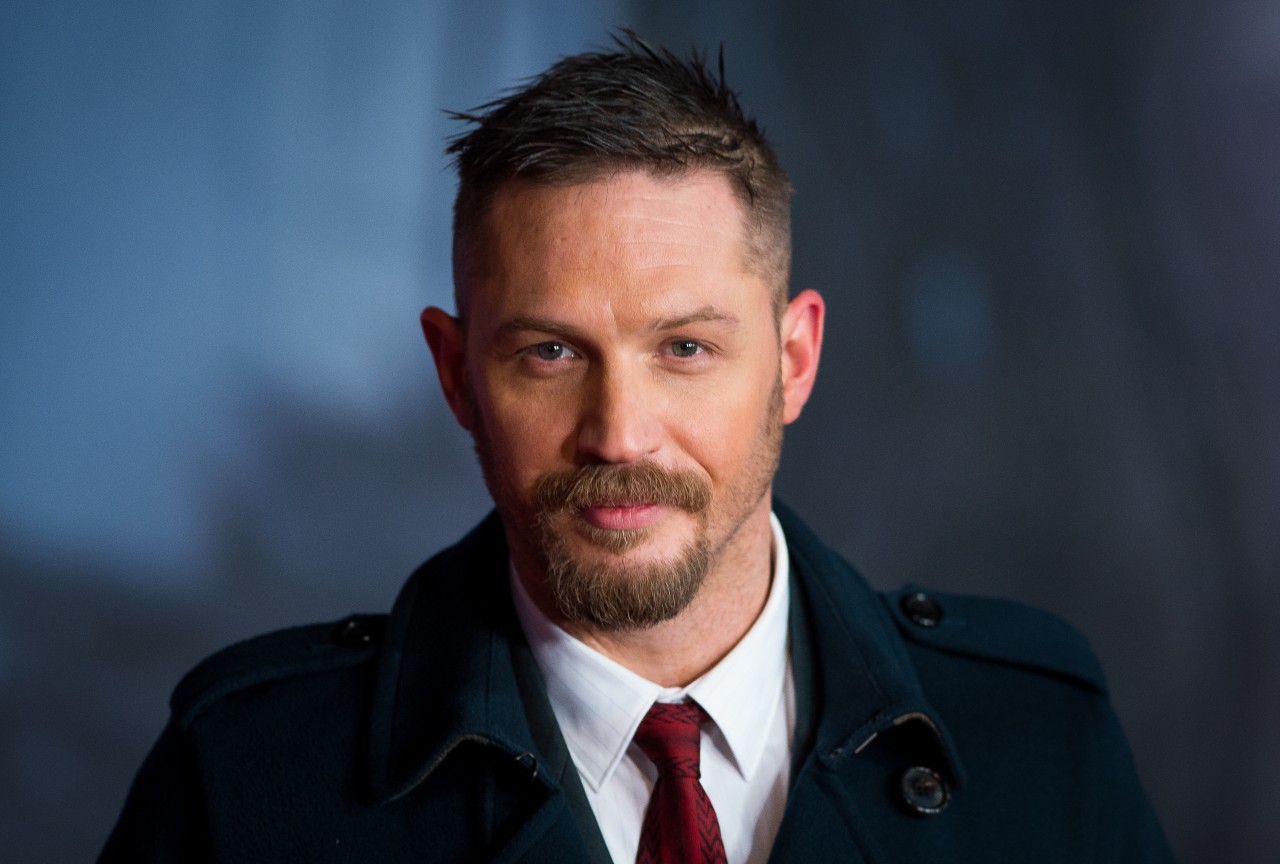 Tom Hardy wears a red tie and navy jacket.
