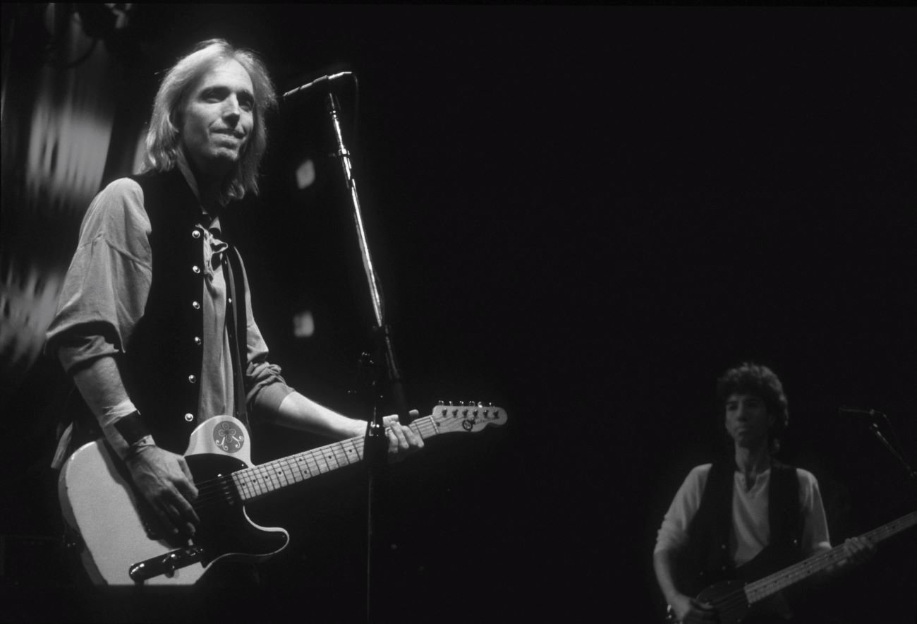 A black and white picture of Tom Petty playing guitar.