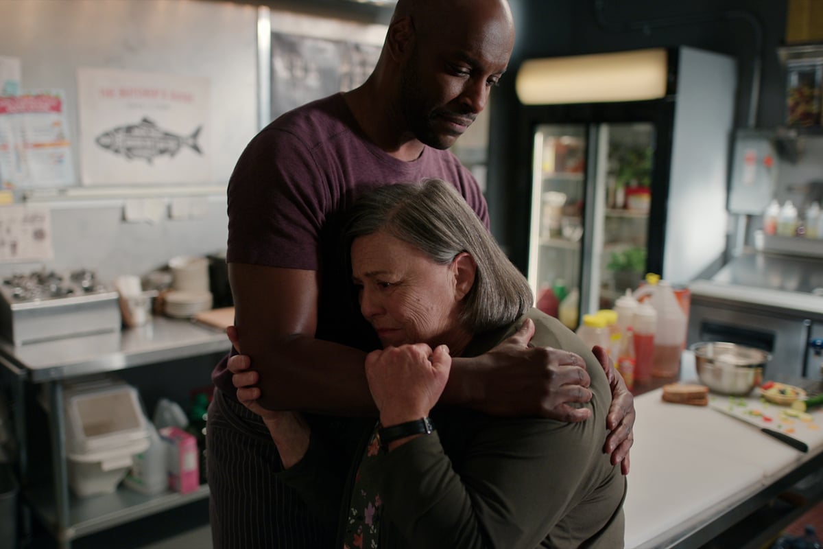 Colin Lawrence as Preacher and Nicola Cavendish as Connie embrace in a kitchen in 'Virgin River'