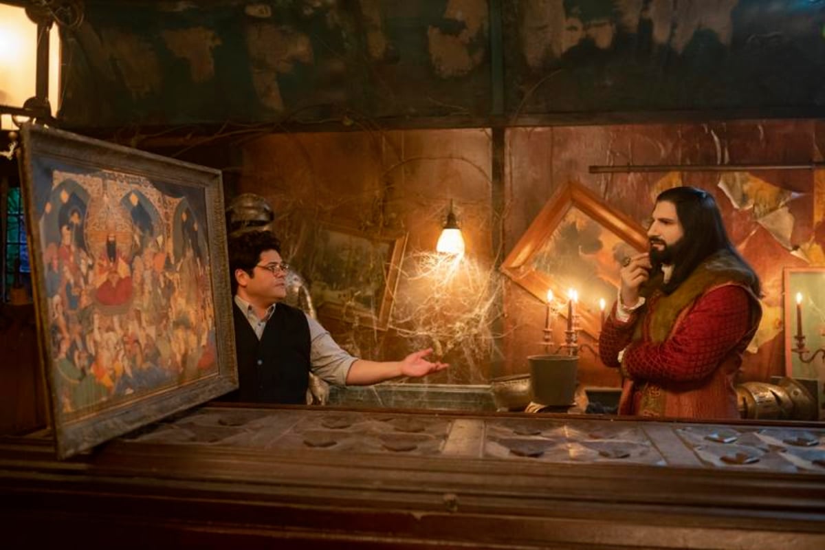 Harvey Guillen as Guillermo and Kayvan Novak as Nandor in What We Do in the Shadows Season 4. Guillermo and Nandor look at a painting of Nandor's 37 wives.