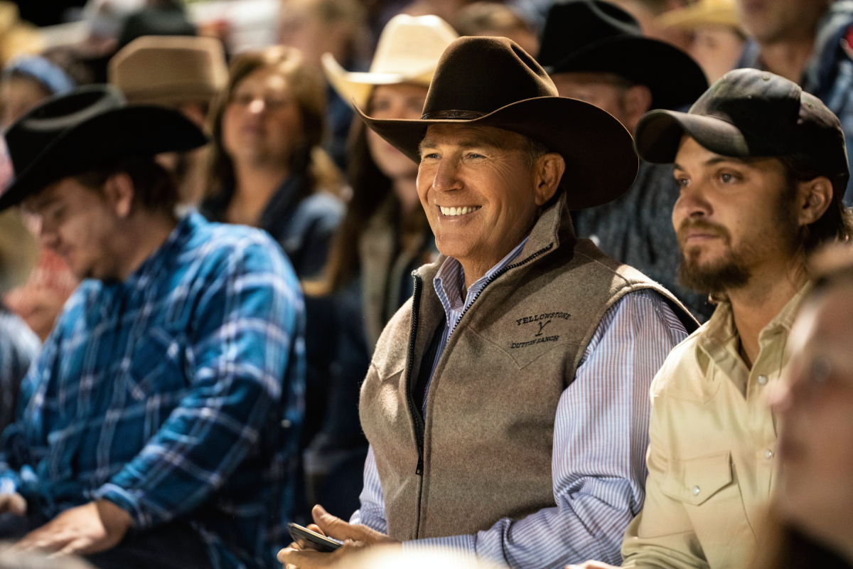 Yellowstone star Kevin Costner smiles as John Dutton in an image from season 3