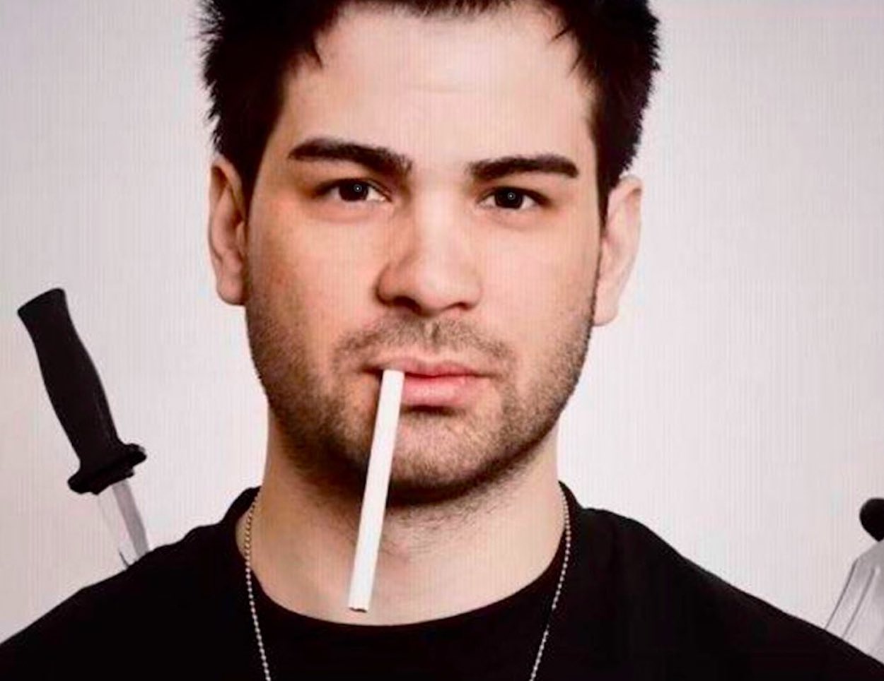 Hunter Moore, founder of IsAnyoneUp.com, with knives on his back and a cigarette in his mouth
