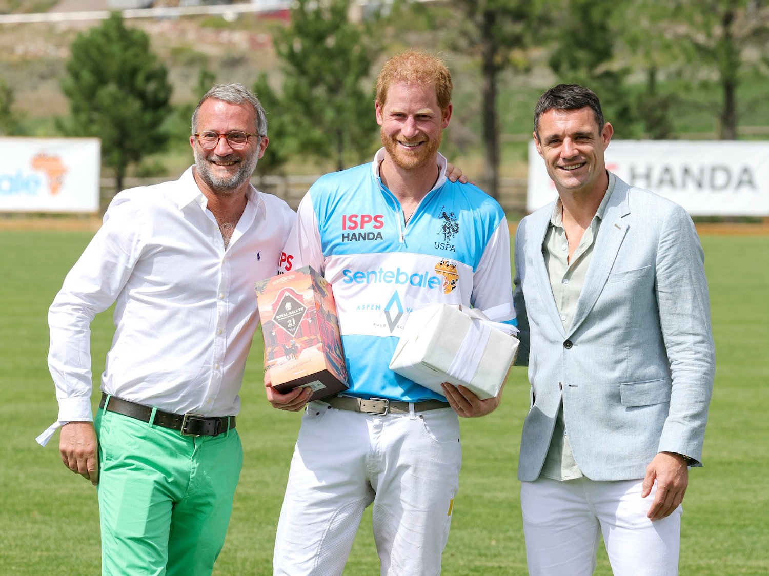 Prince Harry wears a brightly colored polo shirt at the Sentebale ISPS Handa Polo Cup as his body language shows relaxed and smiling gestures