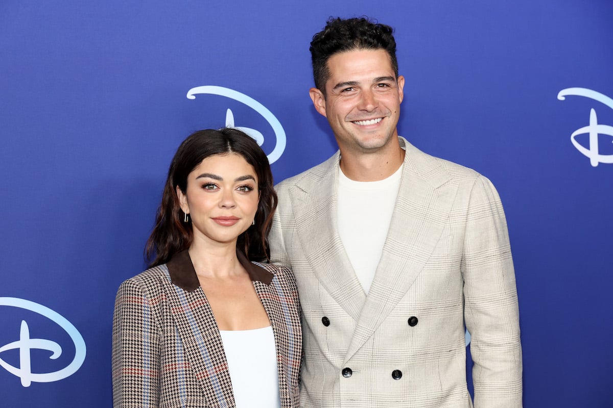 Sarah Hyland and Wells Adams, who just had their wedding, posing together in front of a blue Disney backdrop
