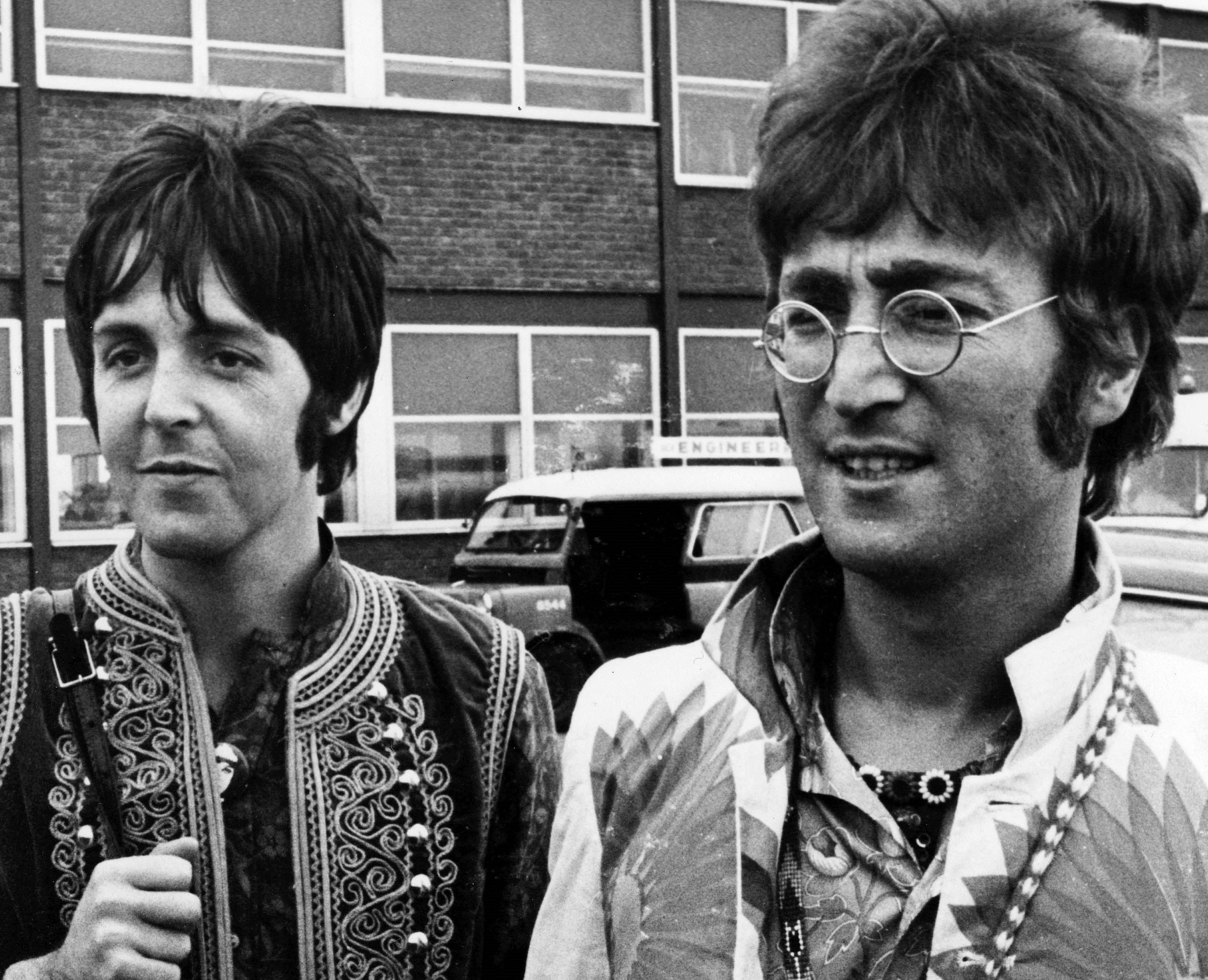 The Beatles' Paul McCartney and John Lennon near cars
