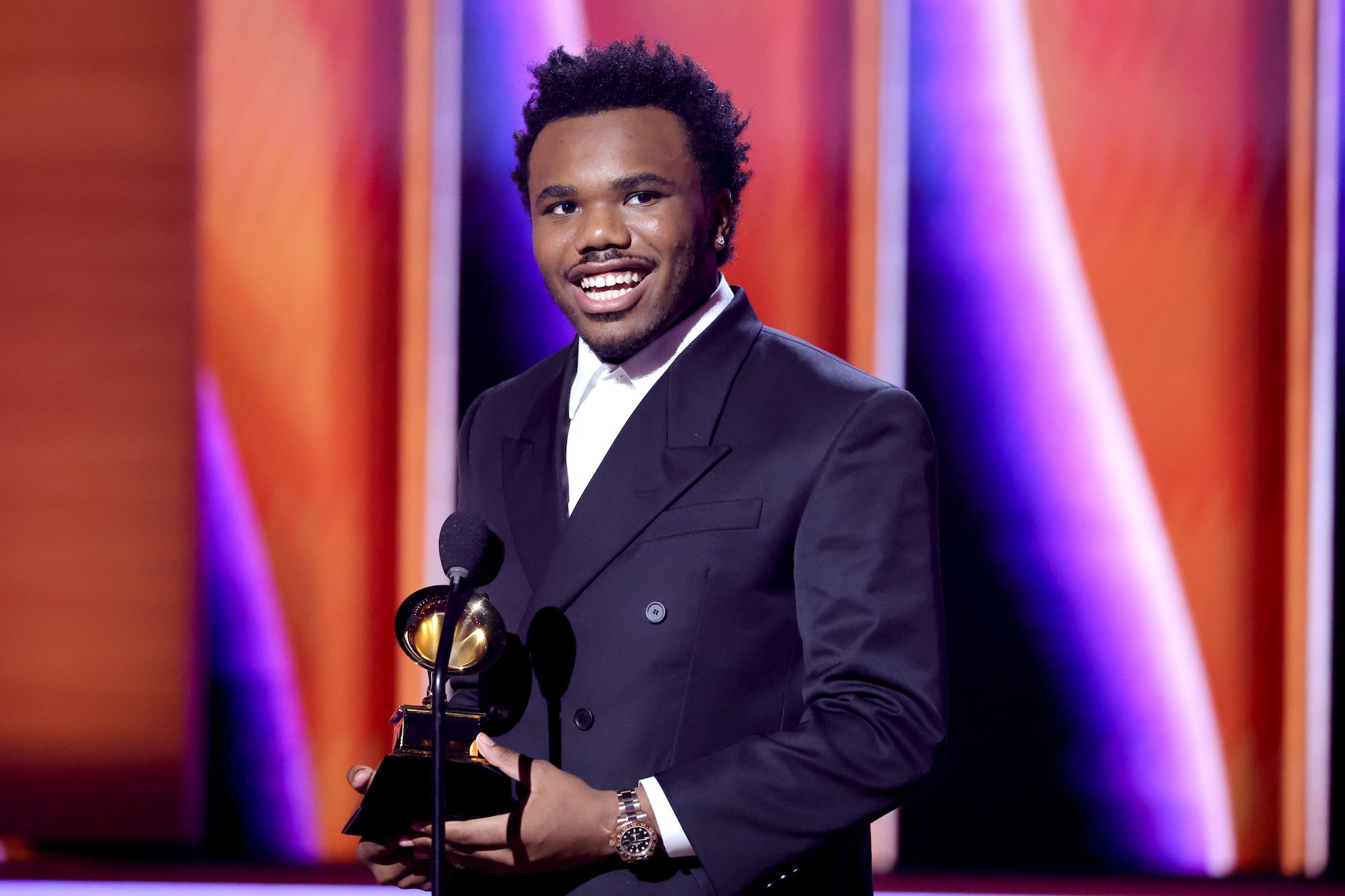 Baby Keem, cousin of Kendrick Lamar, wearing a suit and holding a Grammy Award