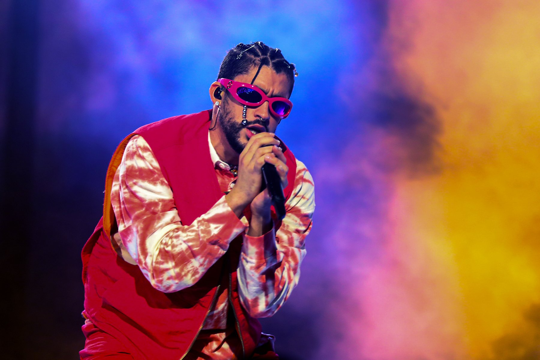 Bad Bunny, who has spoken about his sexuality in the past, wearing red and holding a microphone on stage.