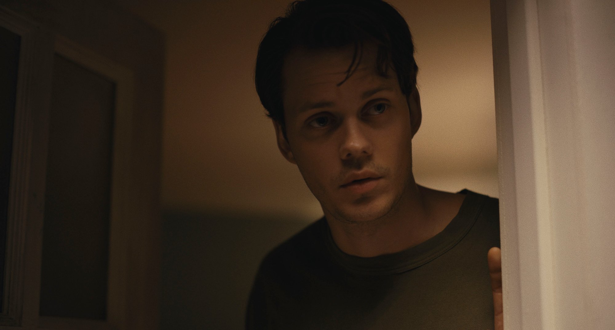 'Barbarian' Bill Skarsgård as Keith looking suspicious wearing a crew neck shirt and holding the door open