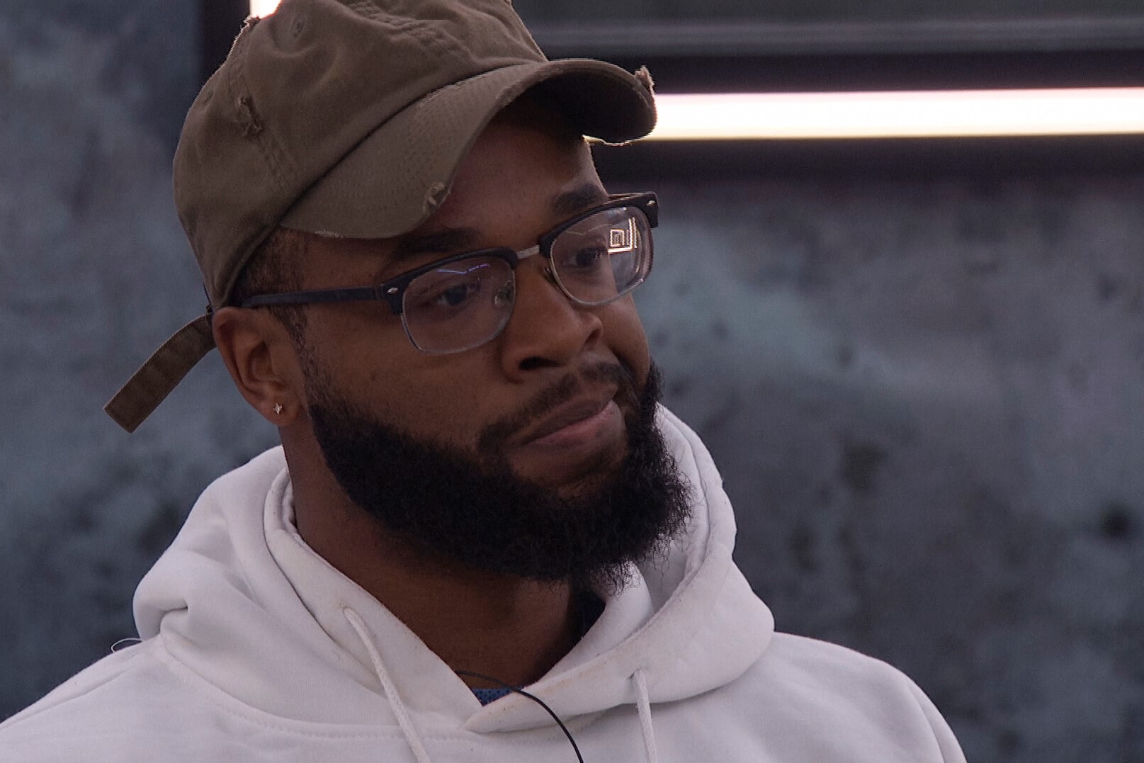 Monte Taylor, who wants to target Michael Bruner next in 'Big Brother 24' on CBS, wears a brown baseball cap, white hoodie, and glasses.