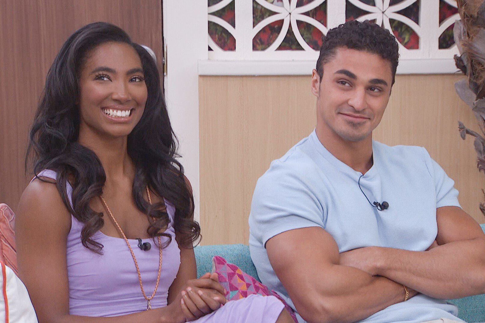 Taylor Hale and Joseph Abdin, who starred together in 'Big Brother 24' on CBS, sit next to each other on a couch. Taylor wears a light purple dress. Joseph wears a light blue shirt.