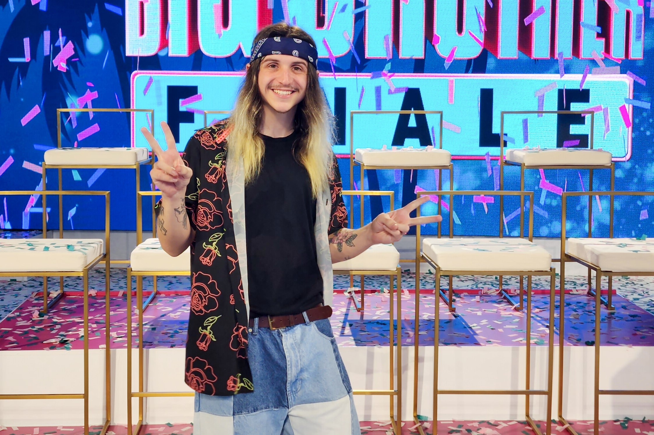 Matthew Turner, who came in third place in 'Big Brother 24' on CBS, wears a black button-up shirt with neon red and yellow roses on it over a black shirt and jeans.