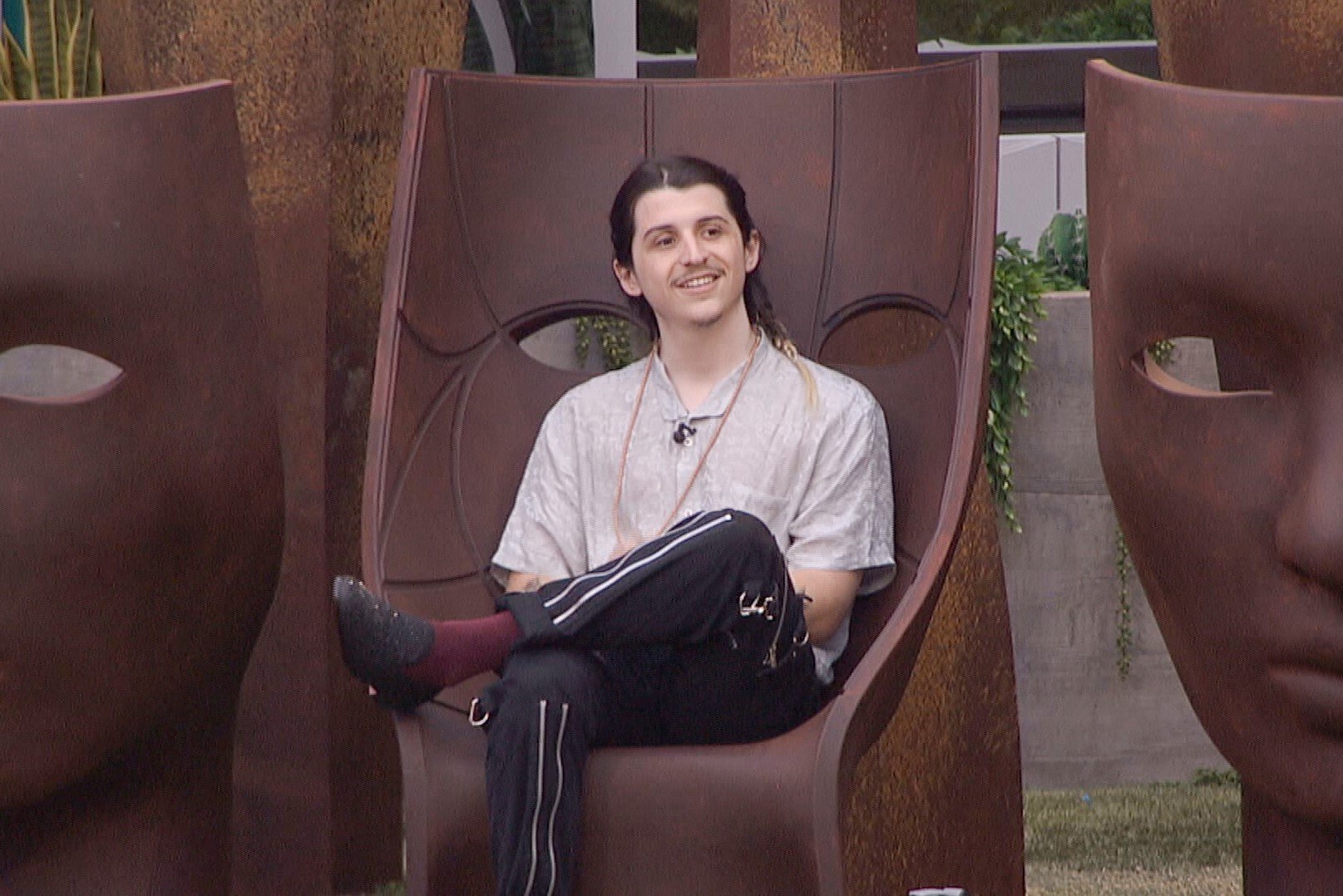 Matthew Turner, who stars in 'Big Brother 24' on CBS, sits in a tiki chair and wears a light gray shirt and black pants.