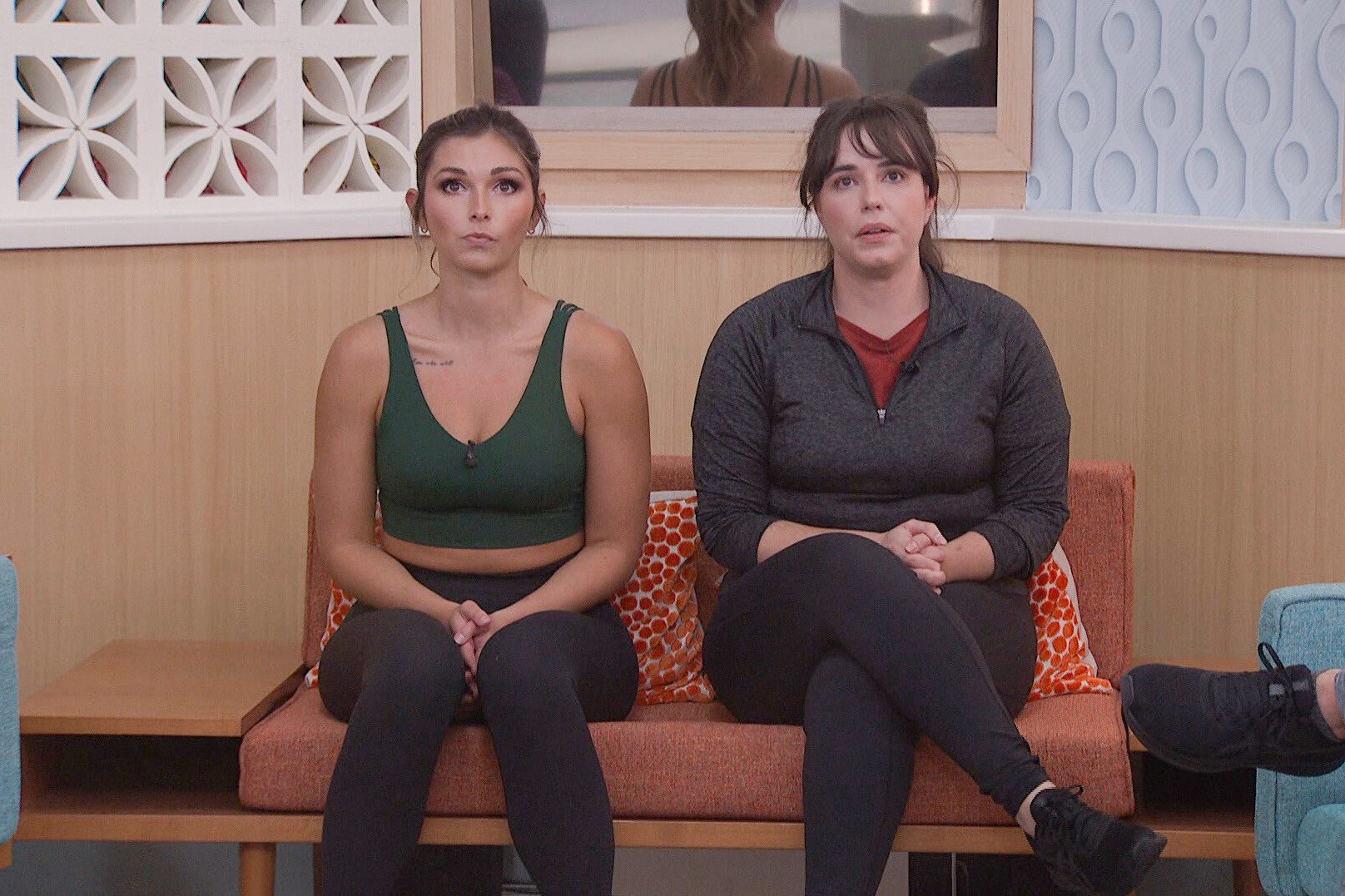 Alyssa Snider and Brittany Hoopes, who, per 'Big Brother 24' spoilers are now working together, sit in the nomination chairs. Alyssa wears a dark green sports bra and black leggings. Brittany wears a dark gray long-sleeved shirt over a red shirt and black leggings.