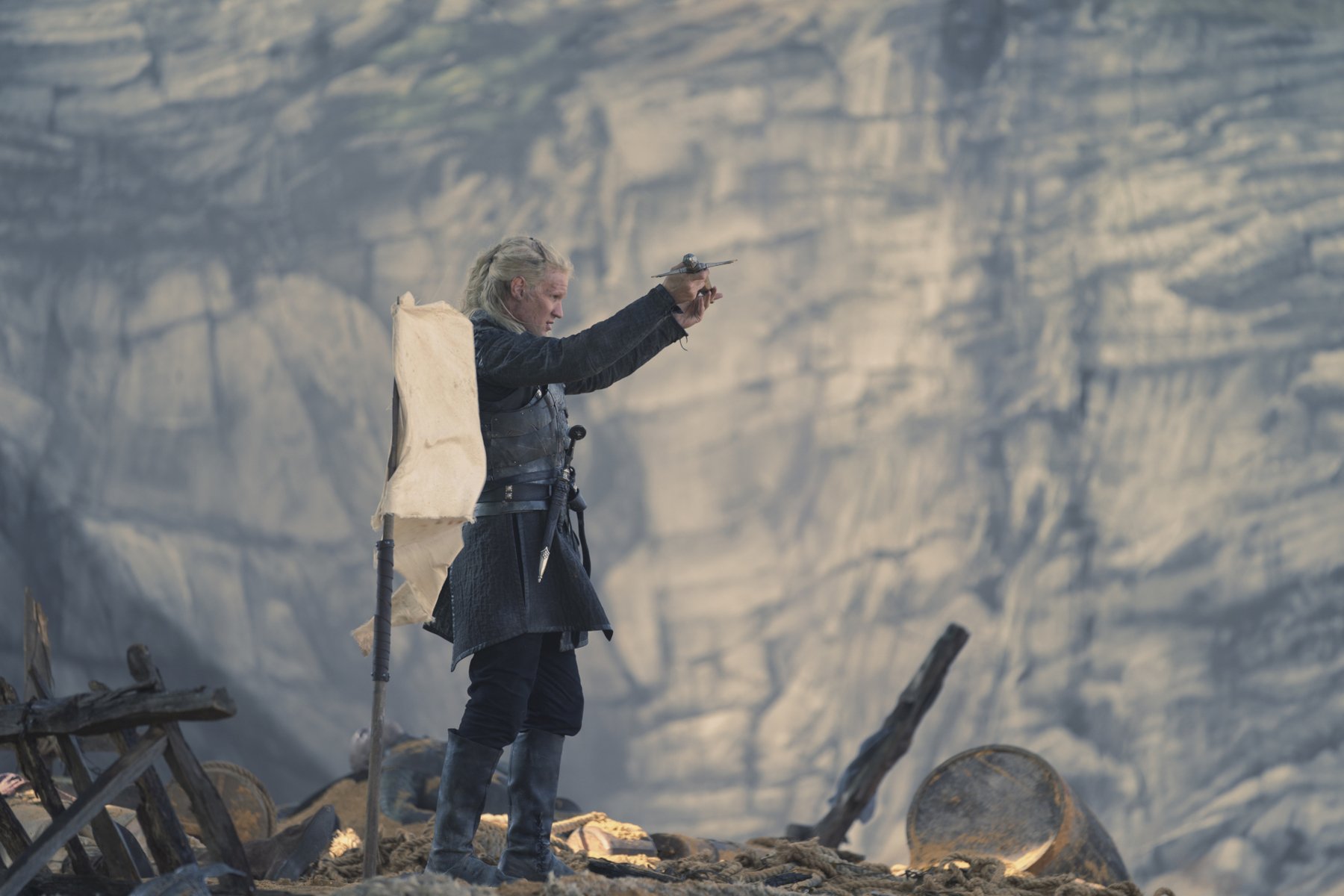 Matt Smith as Daemon Targaryen in 'House of the Dragon' Episode 3. He's standing next to a white flag of surrender and holding up his sword.