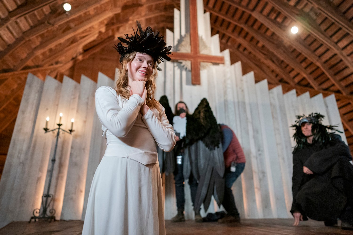 The Netflix thriller 'Devil in Ohio' stars Madeleine Arthur as Mae, seen here wearing a white dress with a crown of black feathers.