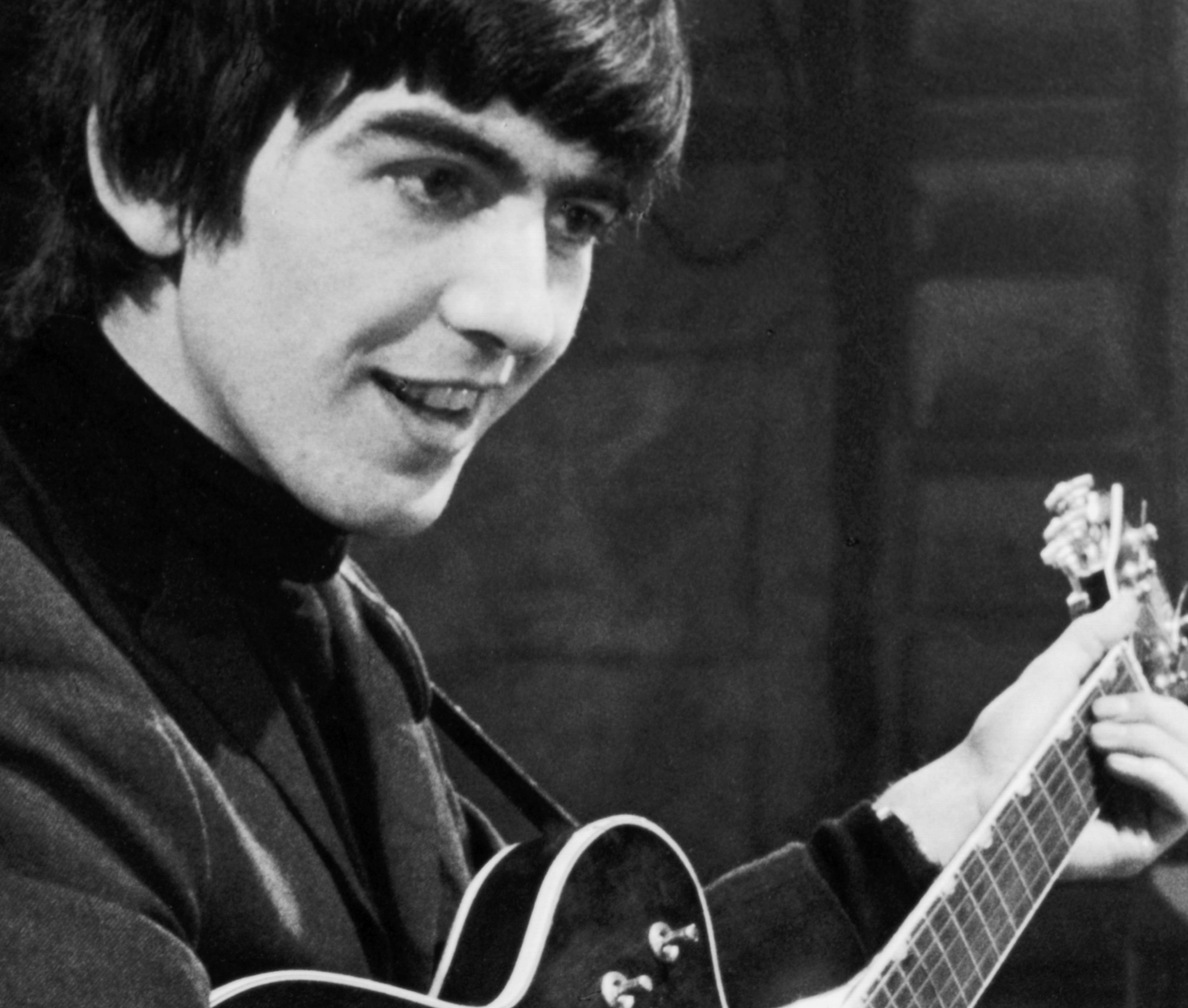 George Harrison holding a guitar during The Beatles' "We Can Work It Out" era