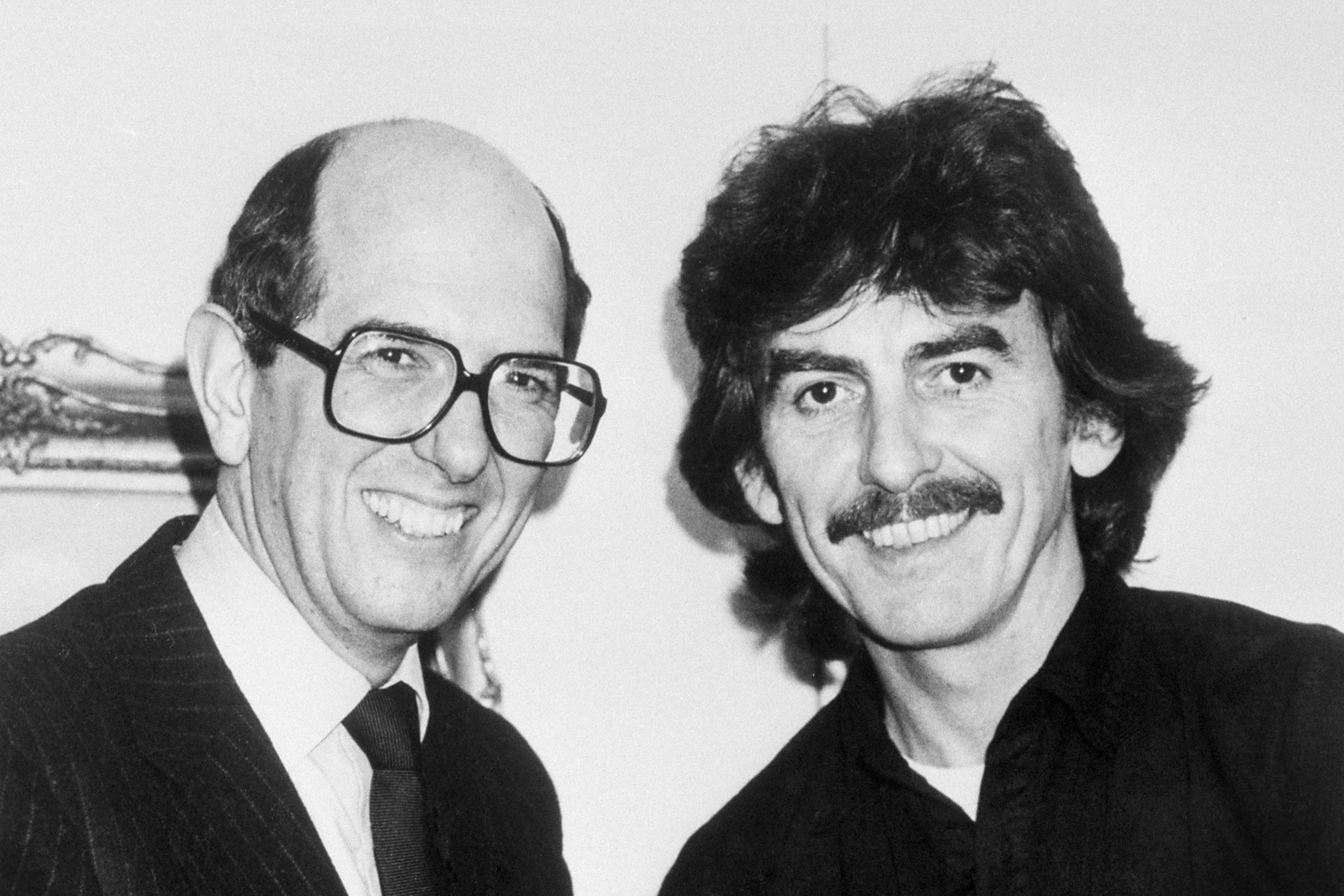 A black and white picture of Denis O'Brien and George Harrison smiling at the camera. 