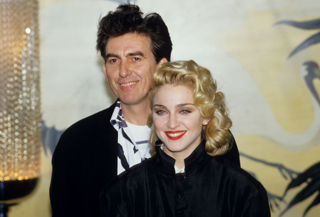 George Harrison stands behind Madonna as they pose for photos. 