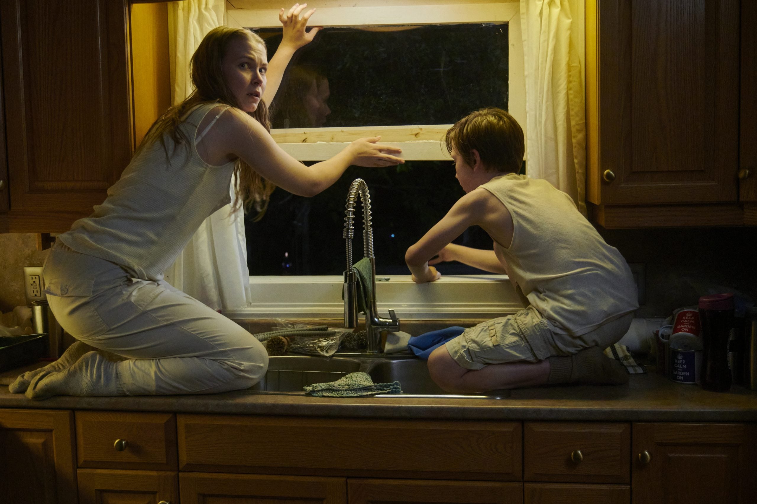 Two children preparing to climb out a window in the Lifetime movie 'House of Chains'