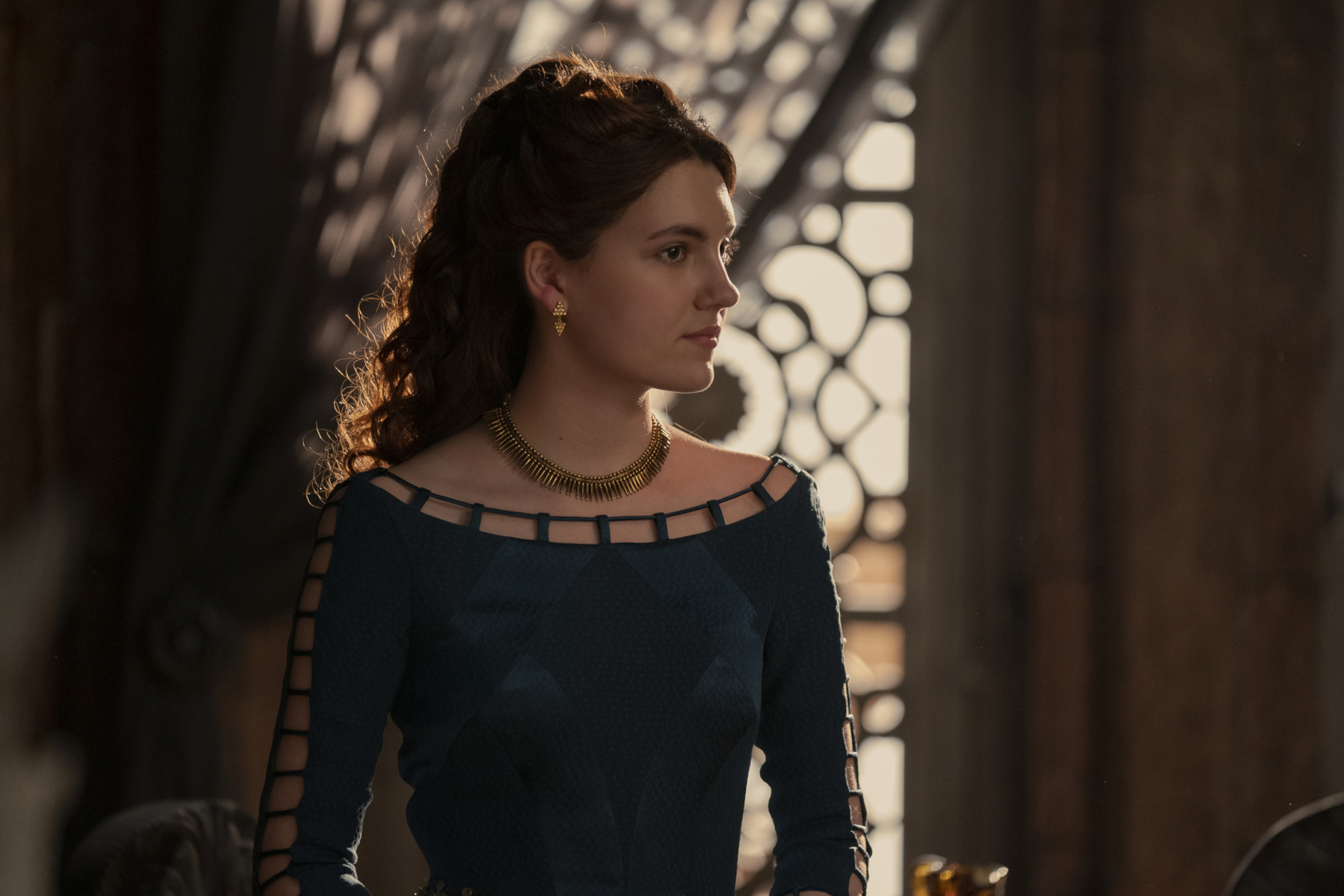 Emily Carey as Alicent Hightower in 'House of the Dragon' Season 1 on HBO. She's wearing a green dress that dips at the shoulders, and her face is turned to the side.